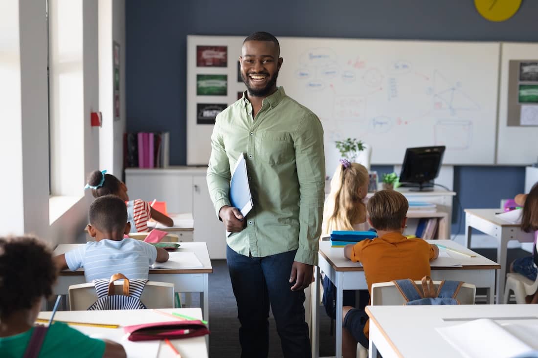 Young male teacher in classroom with elementary students.